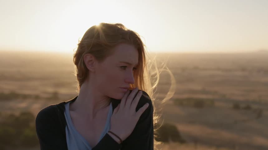 A woman holds her shoulder on a windy day