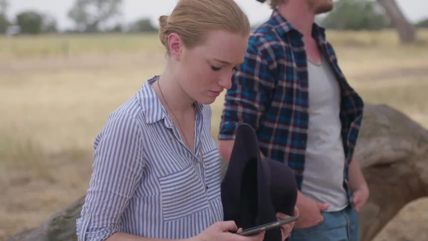 Woman looking at smartphone stands next to man