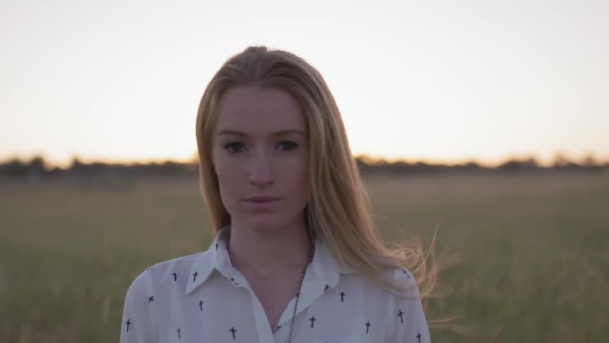 Woman standing in field during sunset on windy evening