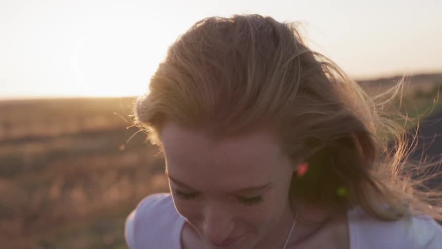 Woman is smiling while walking down country road at sunset
