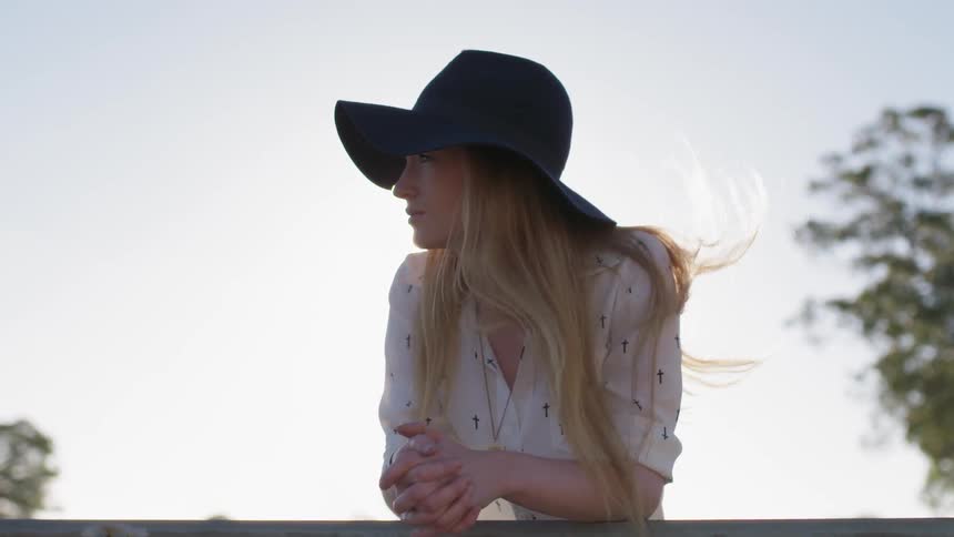 A woman leans on the railing as her hair blows in the breeze
