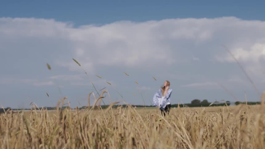 A woman stands in a wheat grass field