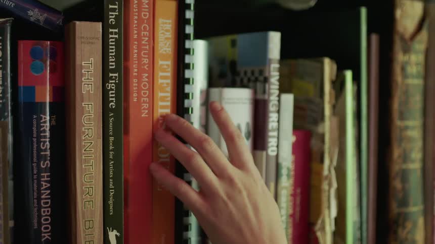 Woman is looking at books on shelf in library