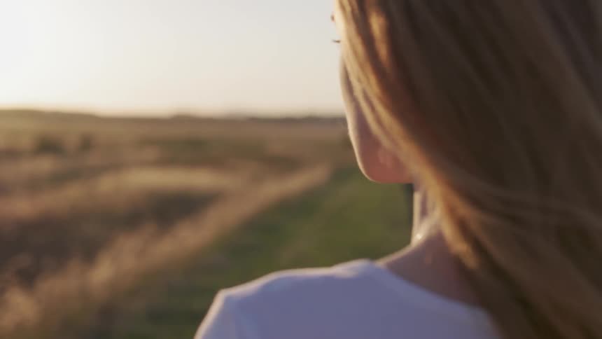 Woman standing in a field looking around at dusk
