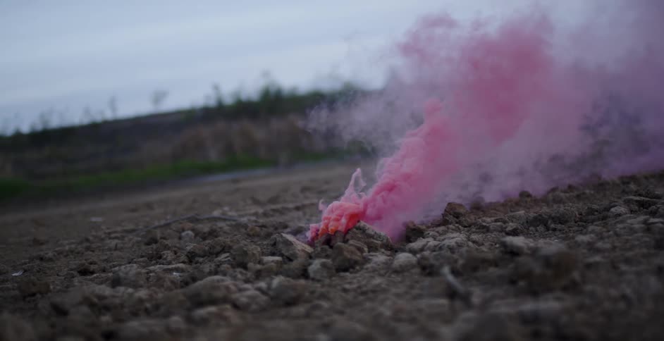 Pink smoke rises from the stone covered ground