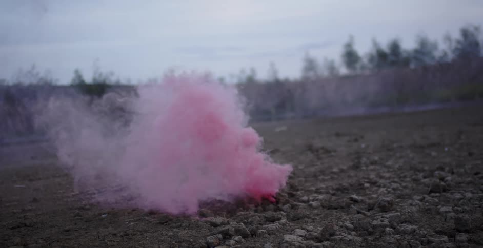 A stream of pink smoke is billowing up in the air in a natural setting