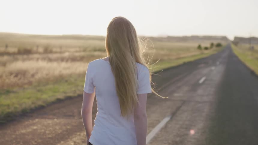 A woman walks down a rural road