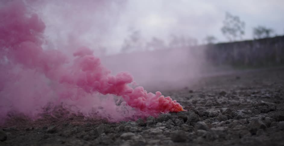 Pink smoke rises from the stone covered ground