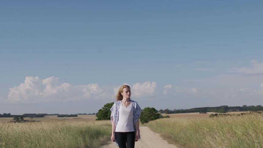A woman walks on a rural dirt path