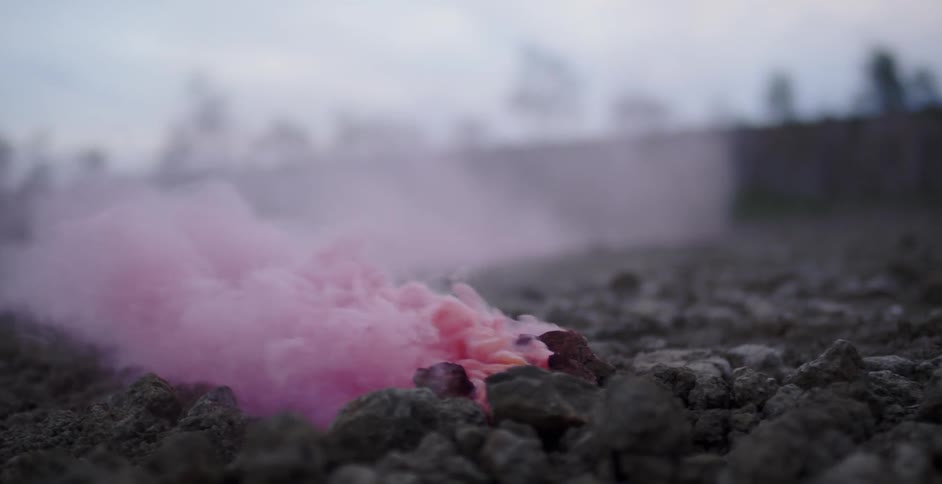 Pink smoke billow up and out from the rocks