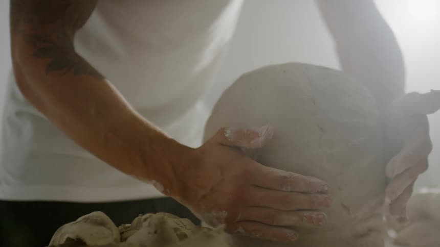 Woman smooths the clay on an artistic piece