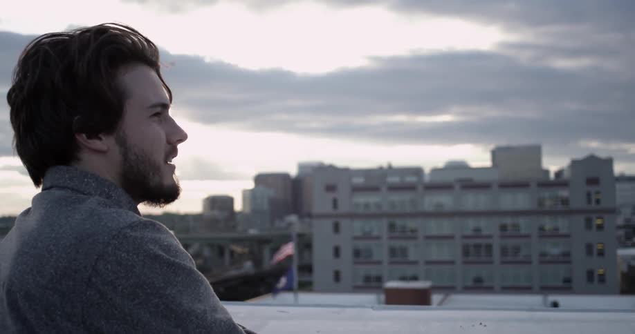 A bearded, brunette man looking out over an urban setting