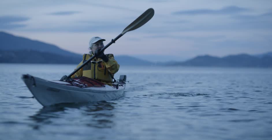 Two people row boats on the water