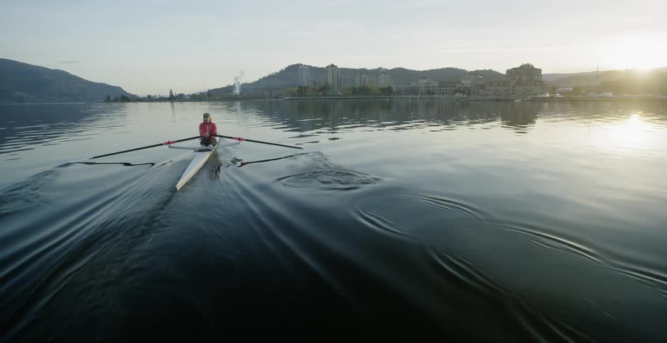 A woman is rowing a skull on a river in daylight