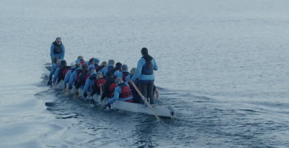 A row team paddles on a lake