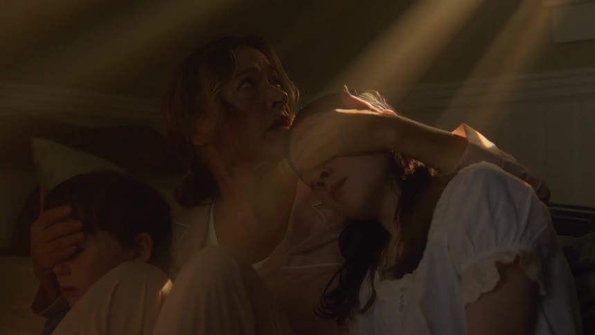 A woman cradles her children in the dark room