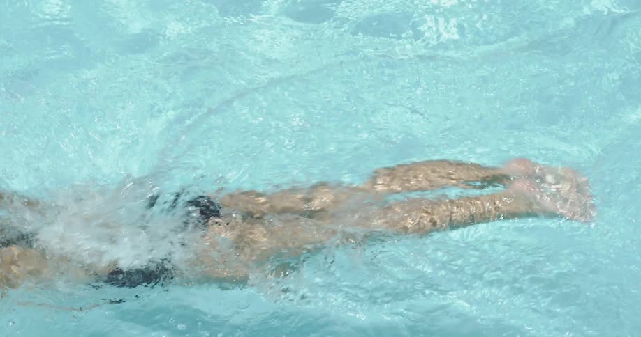 A swimmer is swimming through a pool on a sunny day
