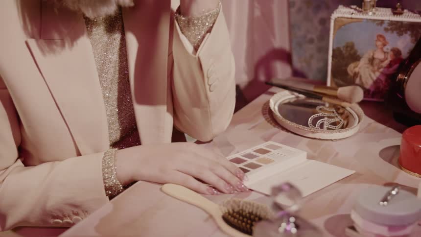 A woman puts on makeup at a table