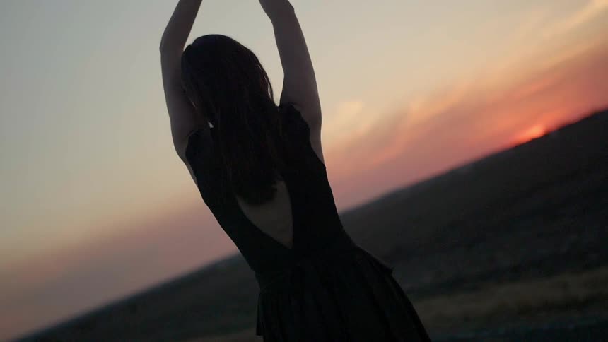 A woman is stretching at sunset