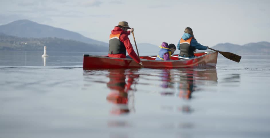 A family are rowing a canoe on a lake in daylight