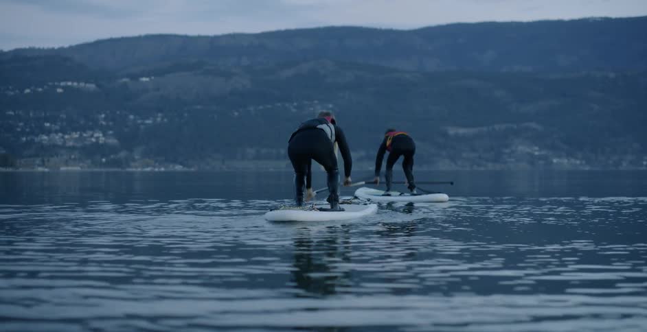 Two women paddle board on a lake