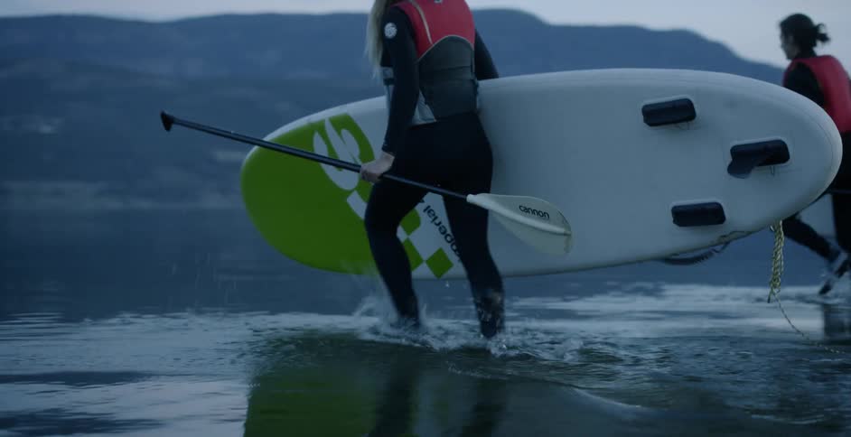 Two women are carrying their paddle boards out into the water at daybreak