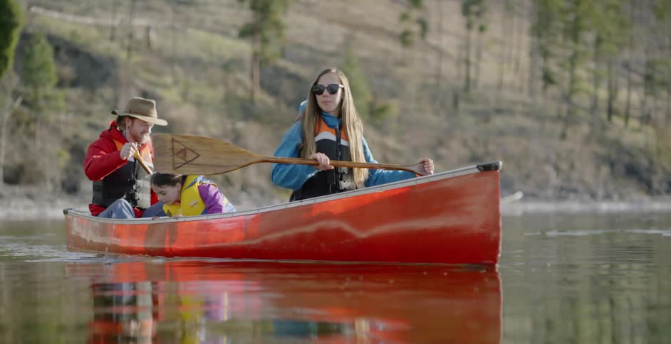 Man and woman paddle a canoe as a young girl sits between them