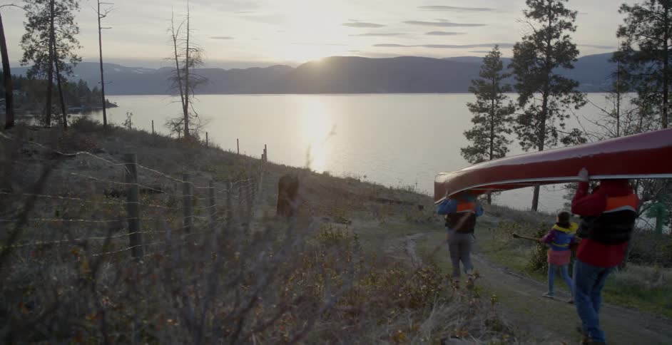 A family canoes at a mountain lake at sunset