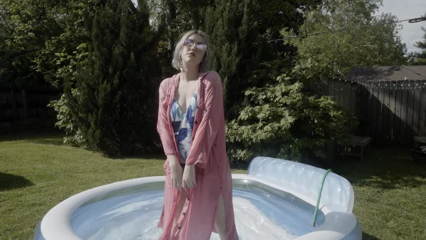 Woman is standing in inflatable pool in yard on sunny day
