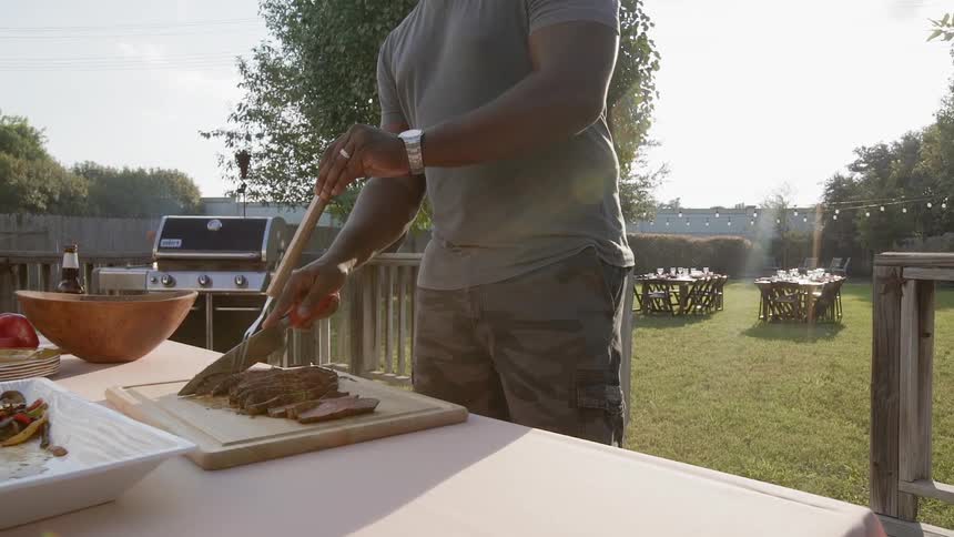 A man is cutting steak in his yard