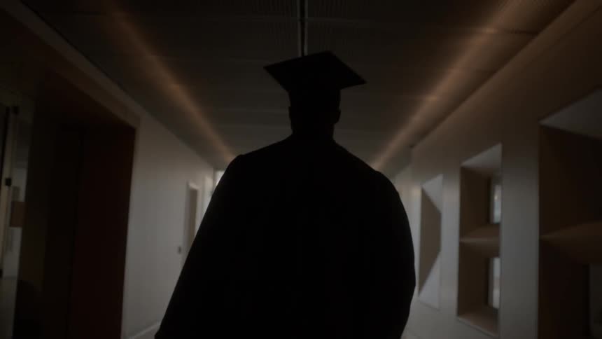 The person walks down the dark hall