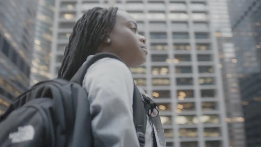 A pedestrian walks in a city with a backpack