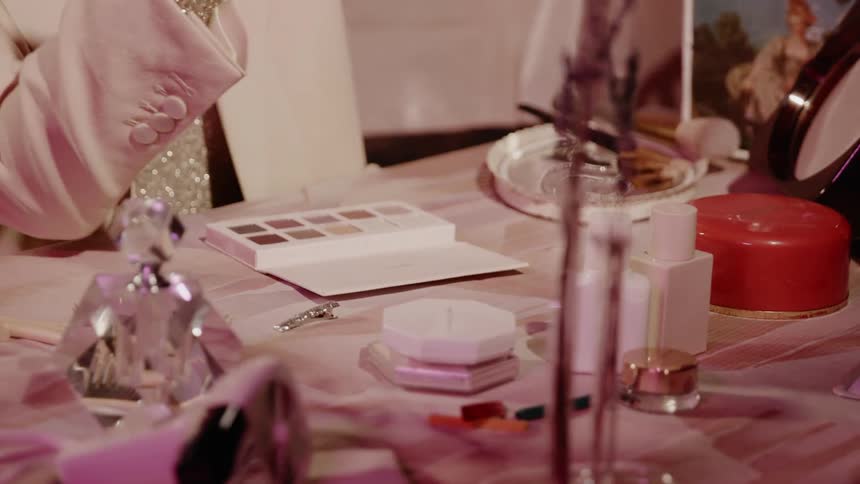 A woman applies makeup at a dressing table