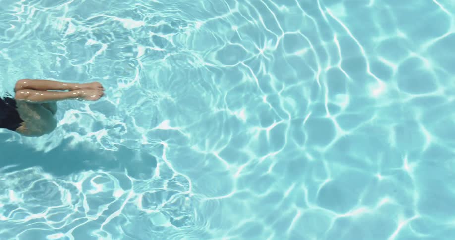 The person kicks their feet in the water as they swim