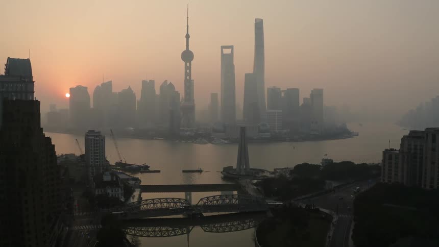 Skyscrapers stand in a foggy city at sunset