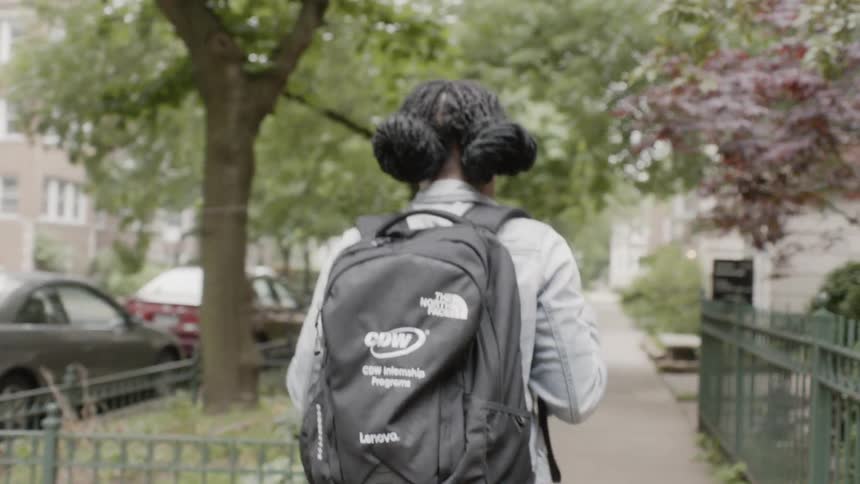 Woman wearing a backpack walks down the sidewalk