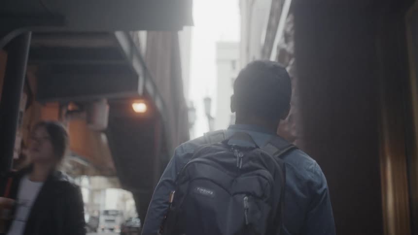 A pedestrian walks in a city with a backpack