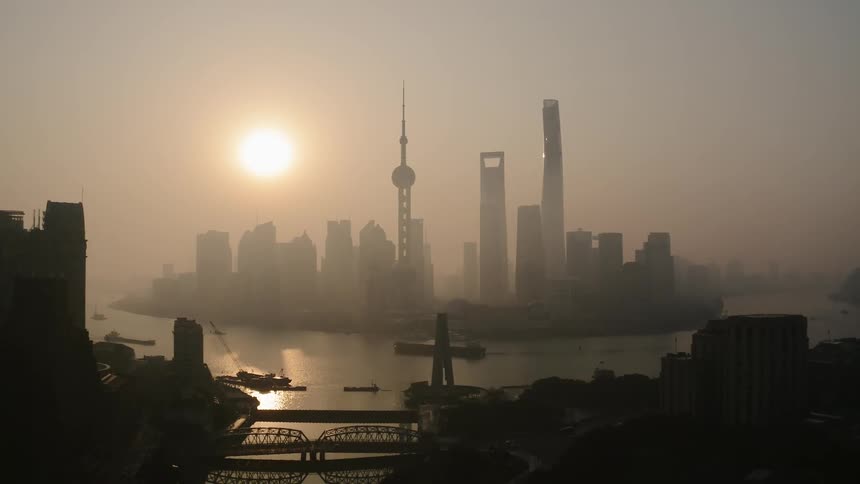 The sun shines behind city skyscrapers