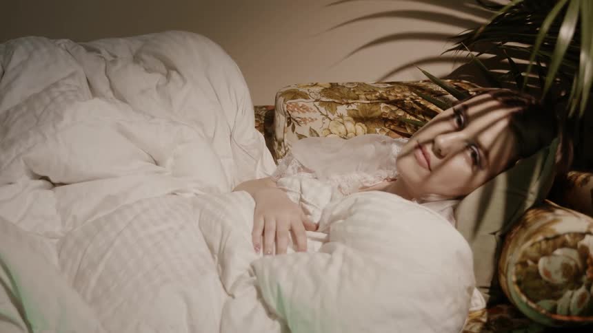 A woman sleeping on a couch is waking up and opening her eyes
