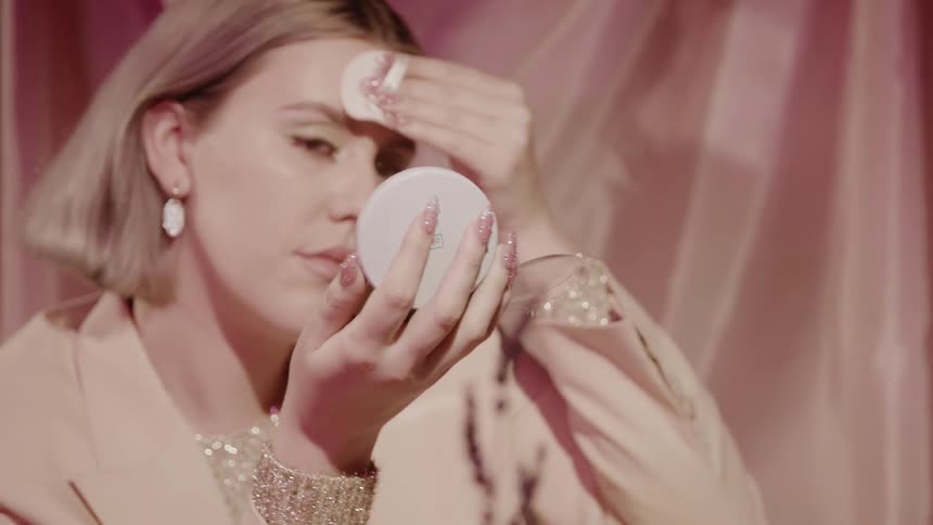 Woman puts makeup on her face at a vanity table