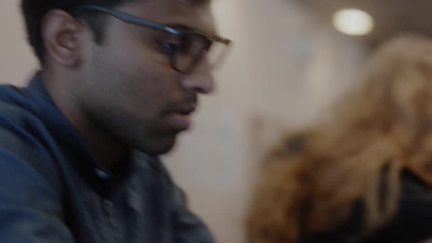 A man types on a laptop in a coffee shop