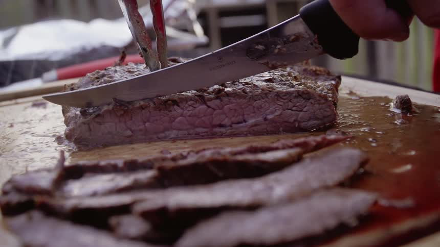 A man cuts thin pieces of meat