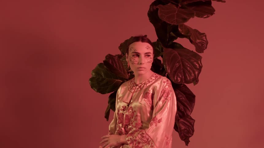 A woman poses in front of a potted plant