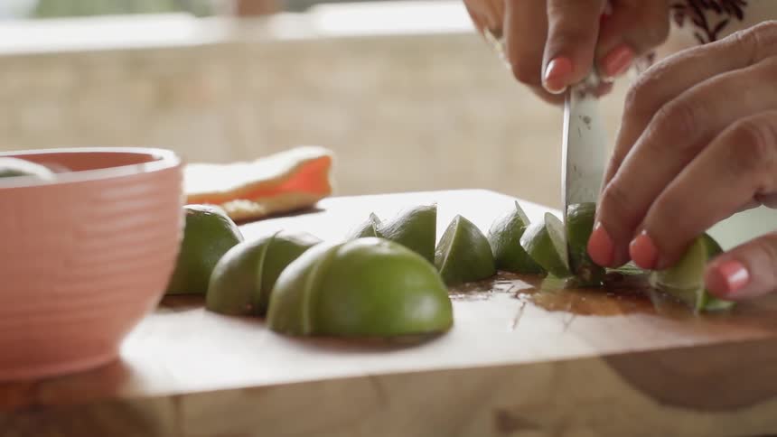 Woman slices limes on a wooden cutting board
