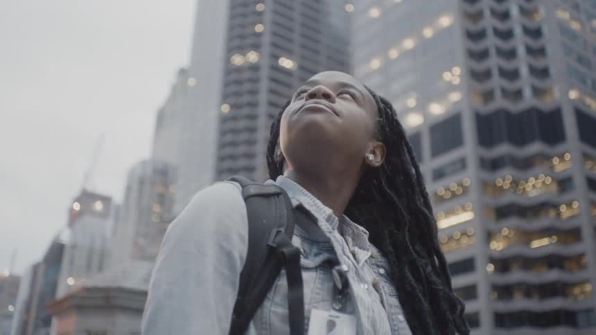 A woman stands looking at city skyscrapers