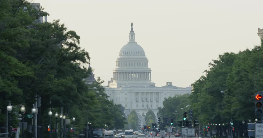 The cars drive on the road near the capitol building