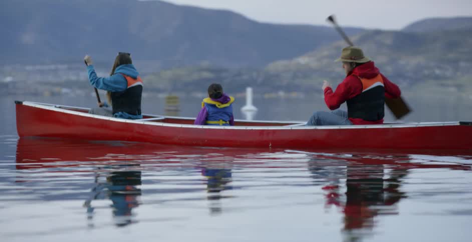 A family canoes on a mountain lake