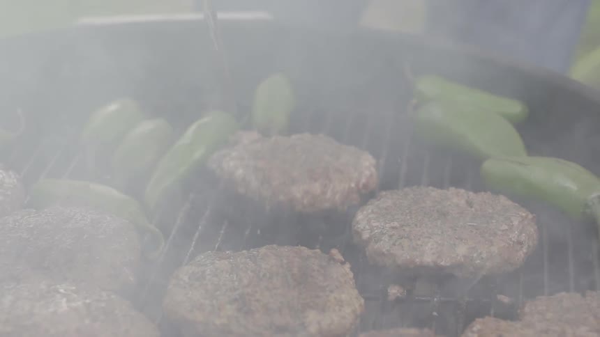 A person is cooking burgers on a grill
