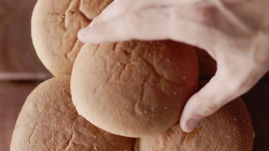 Person places a bun on top of a pile of buns