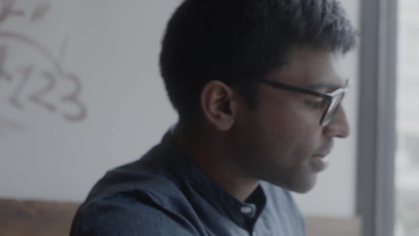 A man is talking and typing on a laptop